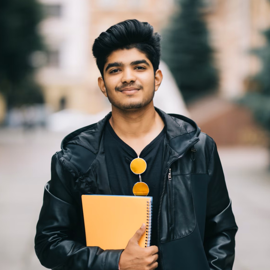 handsome-young-indian-student-man-holding-notebooks-while-standing-street_231208-2771