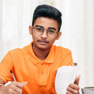 Young Boy preparing for exam , writing in a notepad doing his school work or homework.
